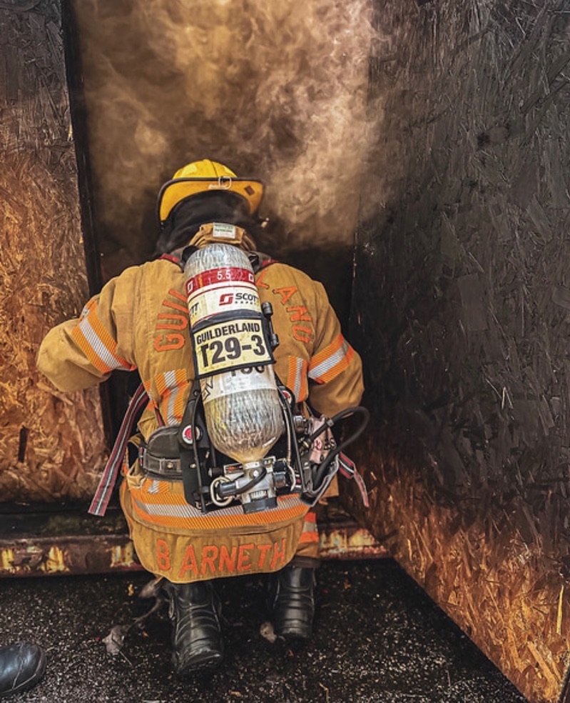 Bill Arneth in turnout gear and SCBA at the doorway of a smoke-filled burn prop